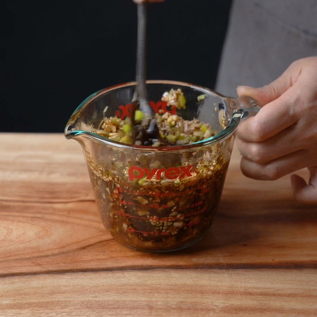Le mélange de marinade sombre en cours de préparation dans un verre doseur.