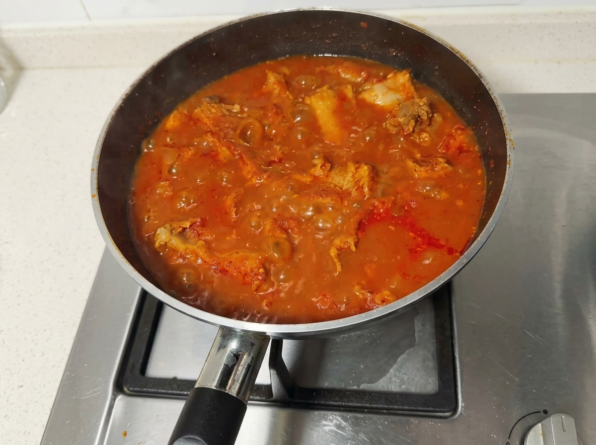 Ragoût de porc rouge et épicé bouillonnant vigoureusement dans une poêle sur la cuisinière.