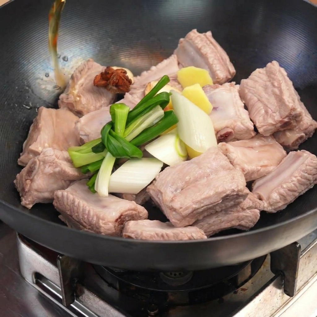 Ribs blanchis dans un wok avec des oignons verts, du gingembre et de lanis étoilé, recouverts de liquide.