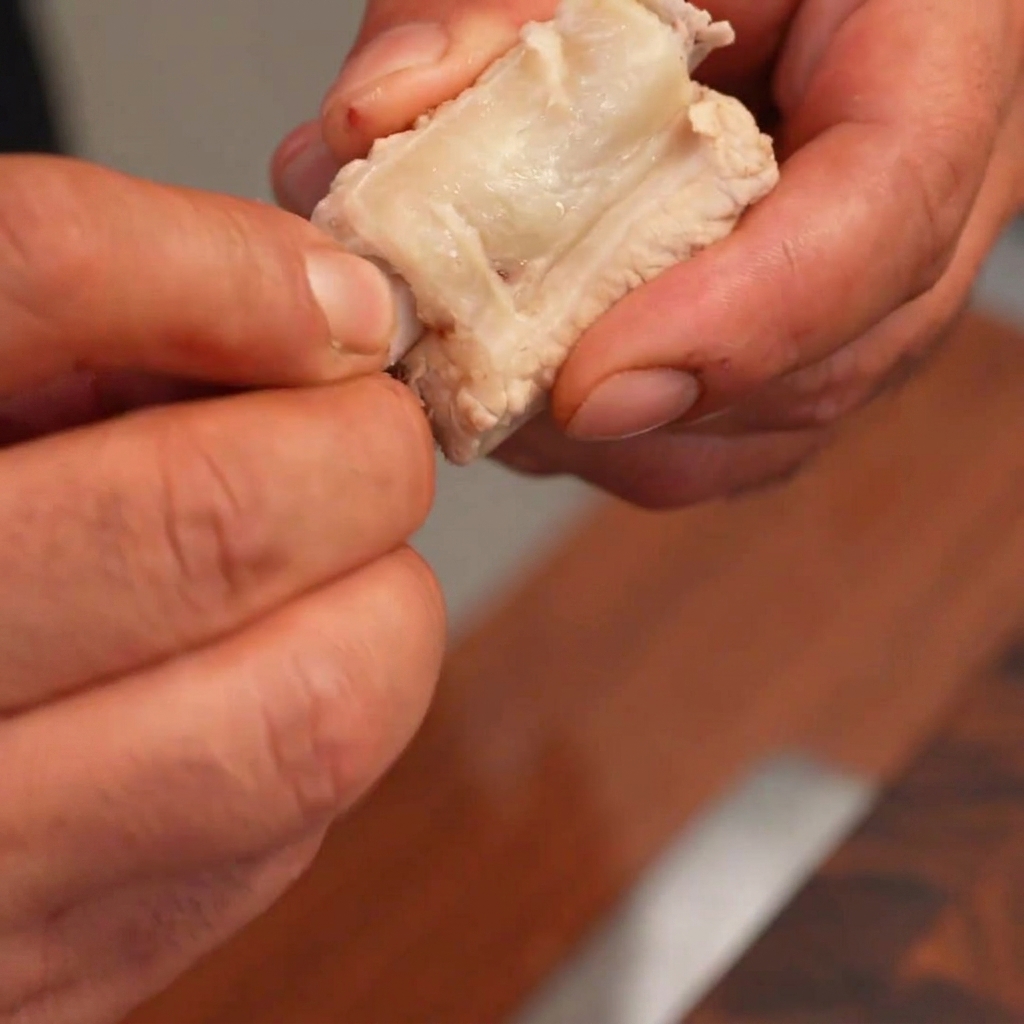 Mains retirant délicatement los central dun rib cuit pour y insérer un gâteau de riz.