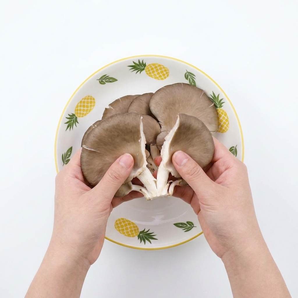 Mains effilochant des pleurotes crus en fines lanières au-dessus dun bol.