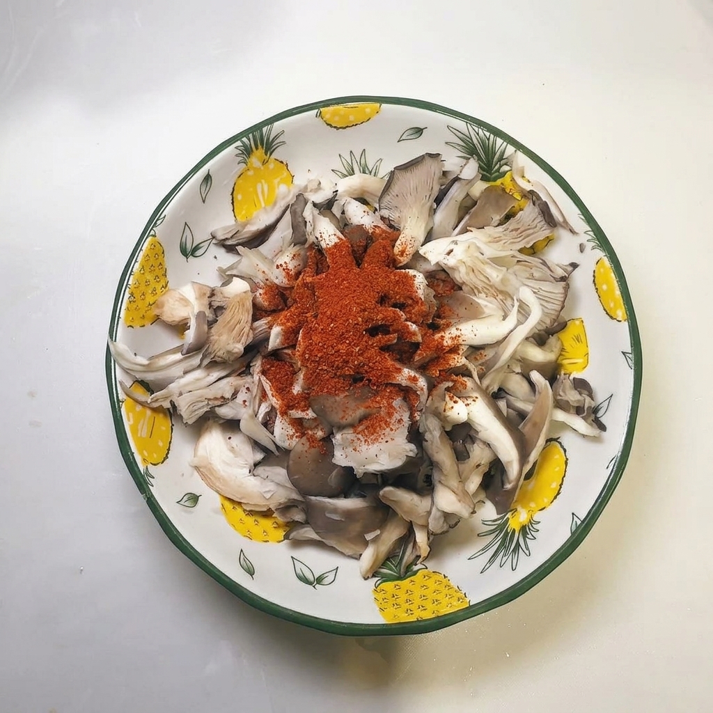 Piment rouge en poudre déposé sur les champignons essorés.