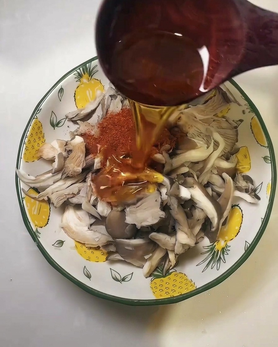 Huile versée à la louche en bois sur les champignons épicés.