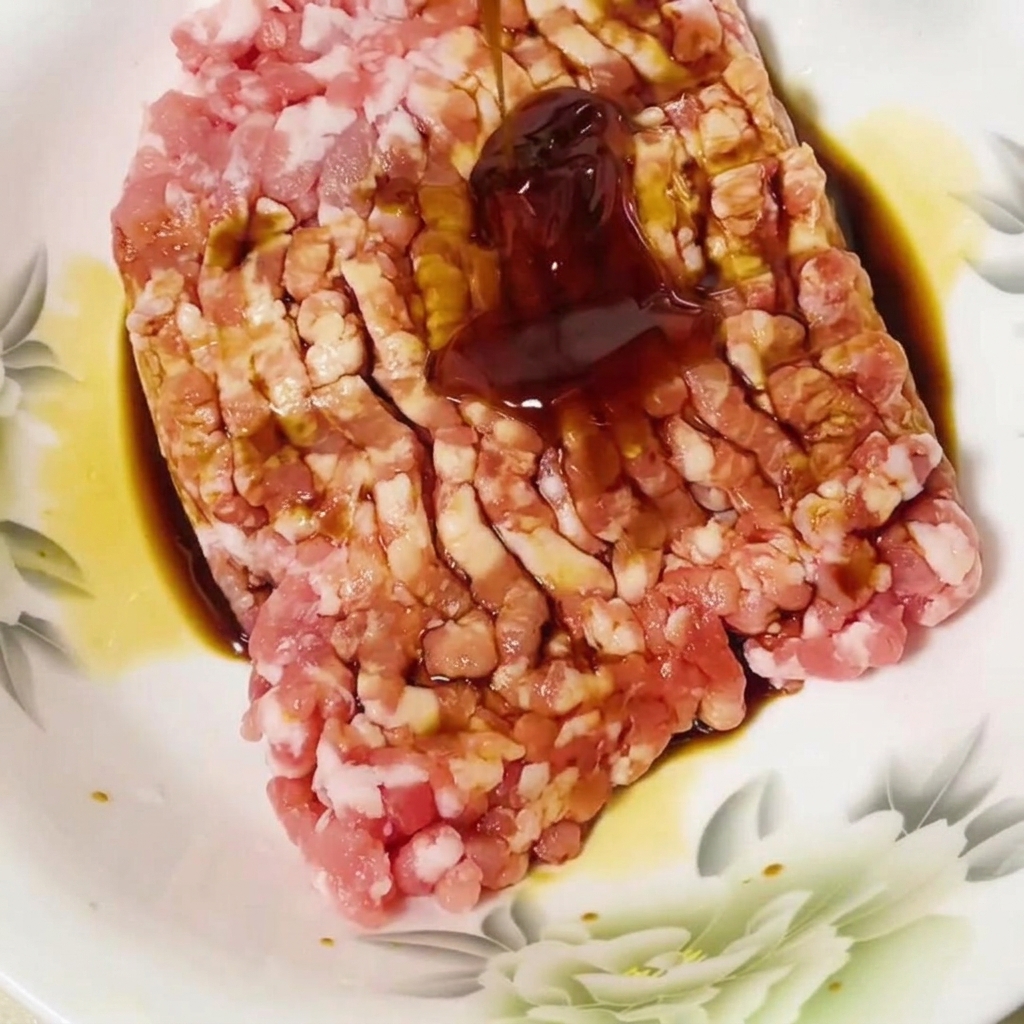 Sauce huître ajoutée au porc haché assaisonné dans un bol.