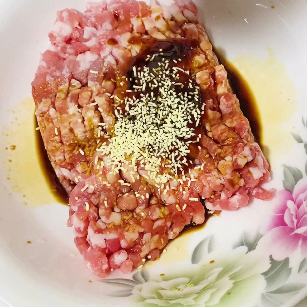 Épices ajoutées au mélange de porc haché et de sauce.