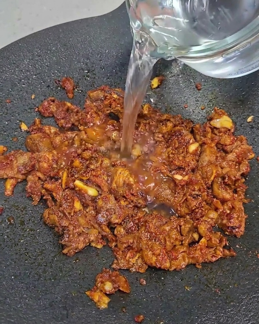 Tranches de poitrine de bœuf cuisant dans une poêle noire.