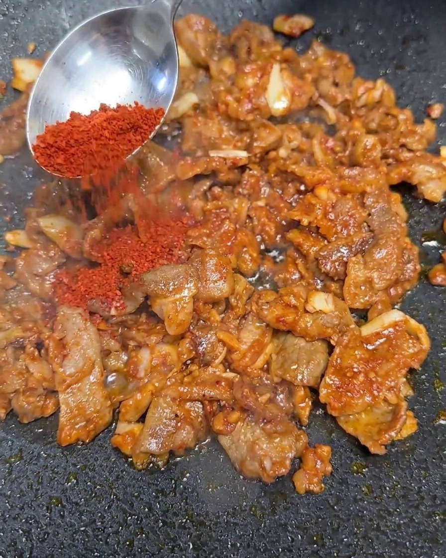 Poudre de piment rouge ajoutée au mélange de bœuf sauté.
