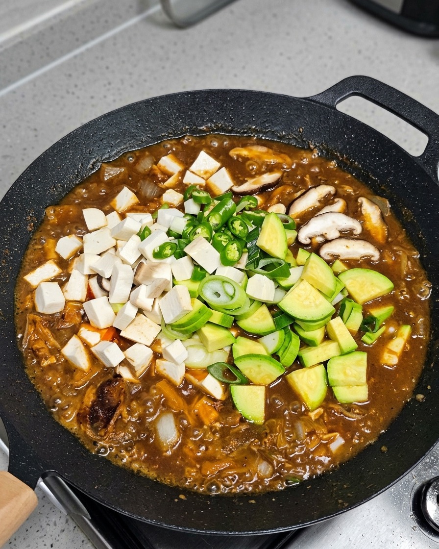 Légumes et tofu ajoutés au ragoût frémissant.