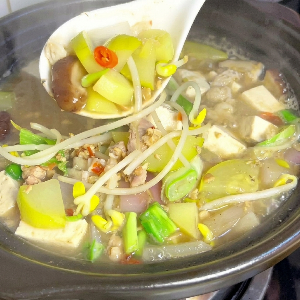 Quartiers de courgette et lamelles de champignons shiitake plongés dans une marmite de bouillon bouillonnant.