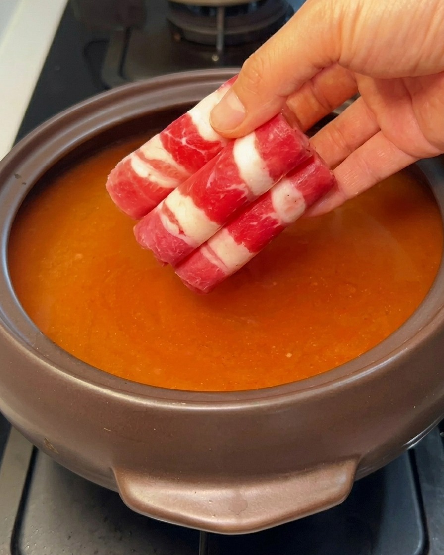 Tranches fines de bœuf gras roulées ajoutées au bouillon frémissant.