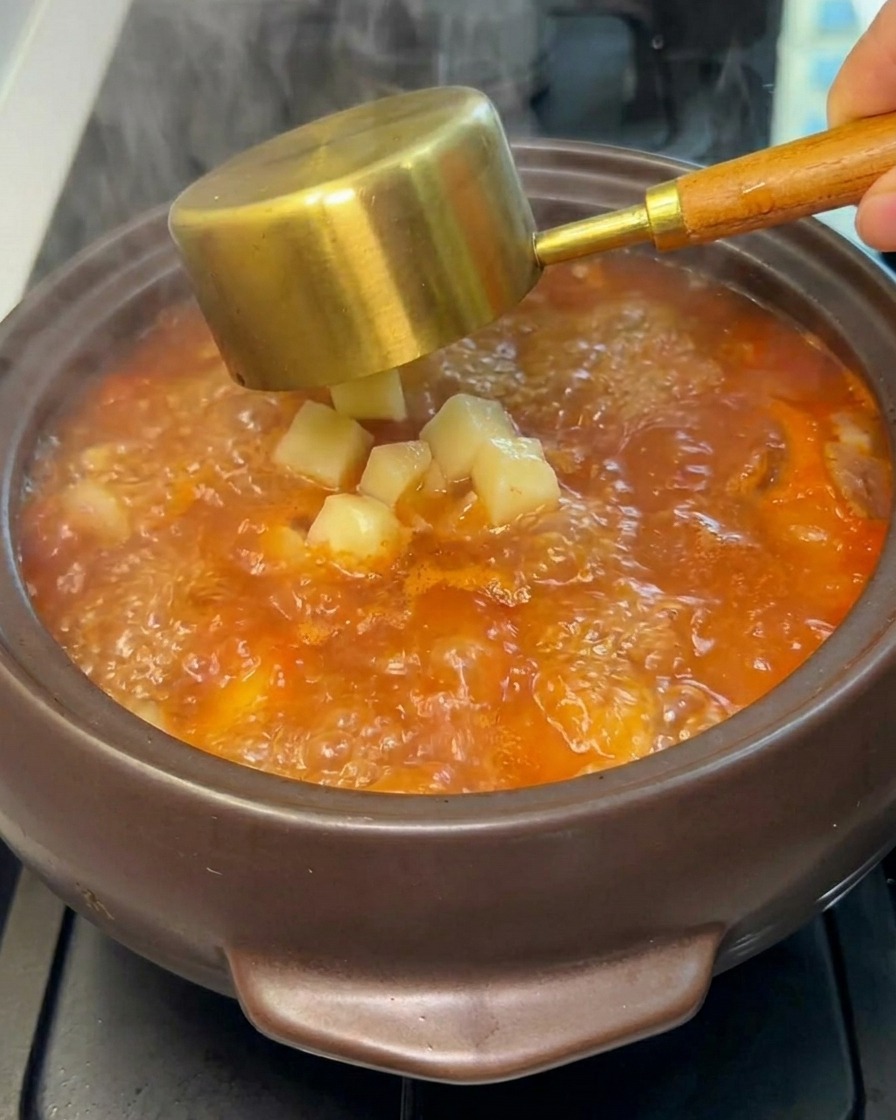 Dés de pommes de terre crus ajoutés dans le ragoût bouillant.