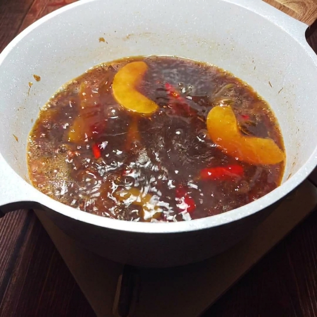 Un bouillon doré et parfumé est filtré à travers un tamis pour retirer les morceaux.