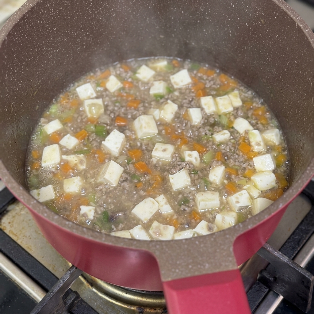 Mélange fécule et eau versé dans la poêle de ragoût de bœuf et tofu mijotant.