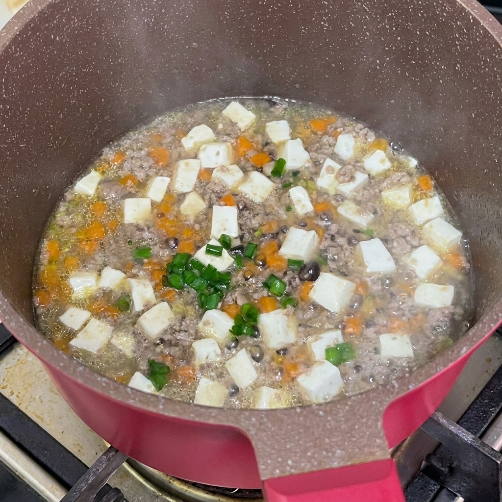 Cébettes vertes fraîchement hachées saupoudrées sur le ragoût de bœuf et tofu terminé dans la poêle.