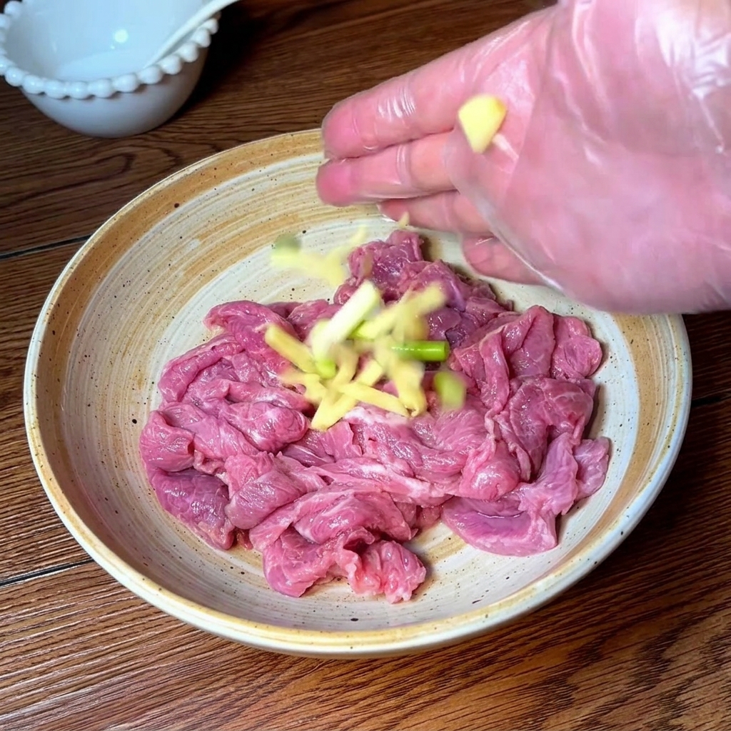 Main gantée assaisonnant et massant des tranches de bœuf avec des aromates et des épices.