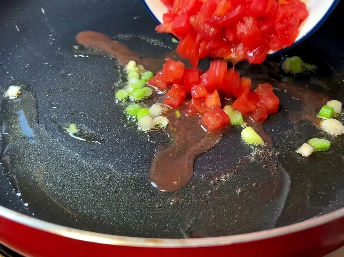 Tomates hachées cuisant dans une poêle jusquà devenir tendres et juteuses.