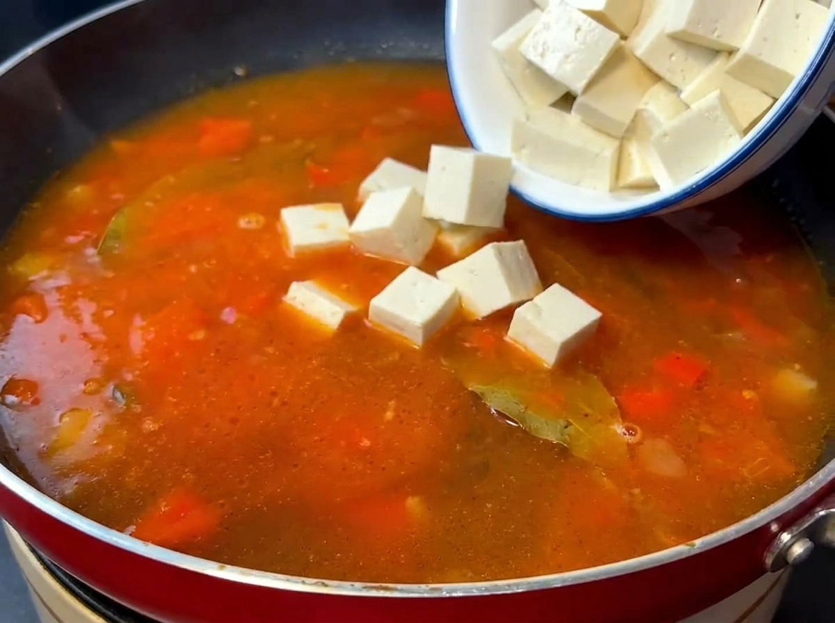 Cubes de tofu soyeux et bœuf sauté ajoutés dans un bouillon de tomate frémissant.