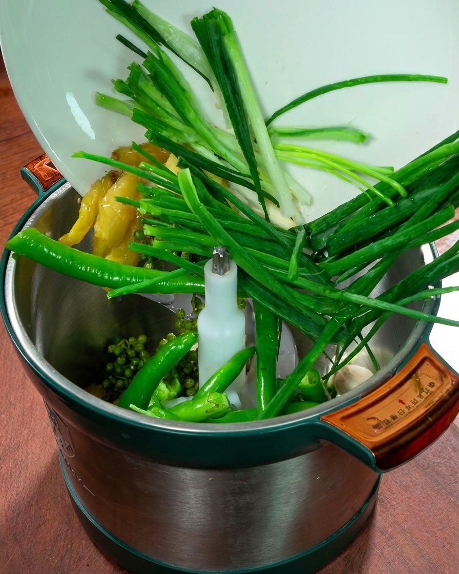 Un robot culinaire rempli doignons verts, gingembre, ail, piments verts frais et poivre du Sichuan.