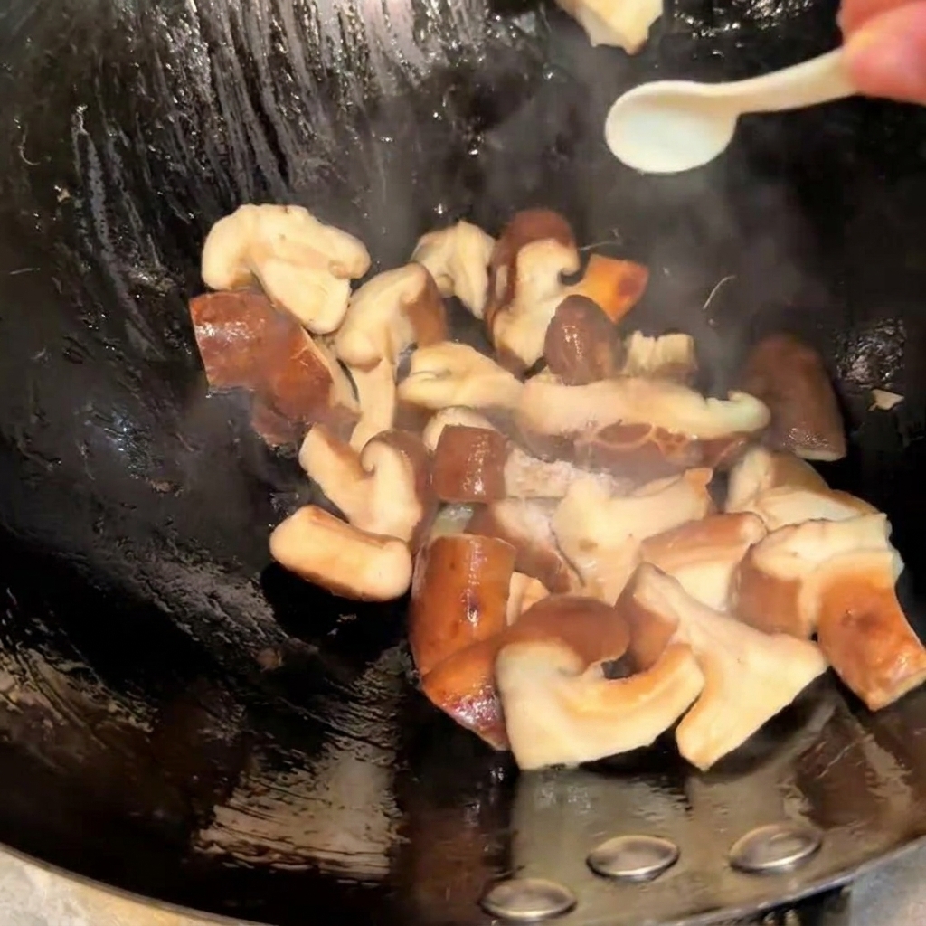 Assaisonnement des champignons shiitake sautés dans un wok avec du sel et de la sauce soja à laide dune petite cuillère.