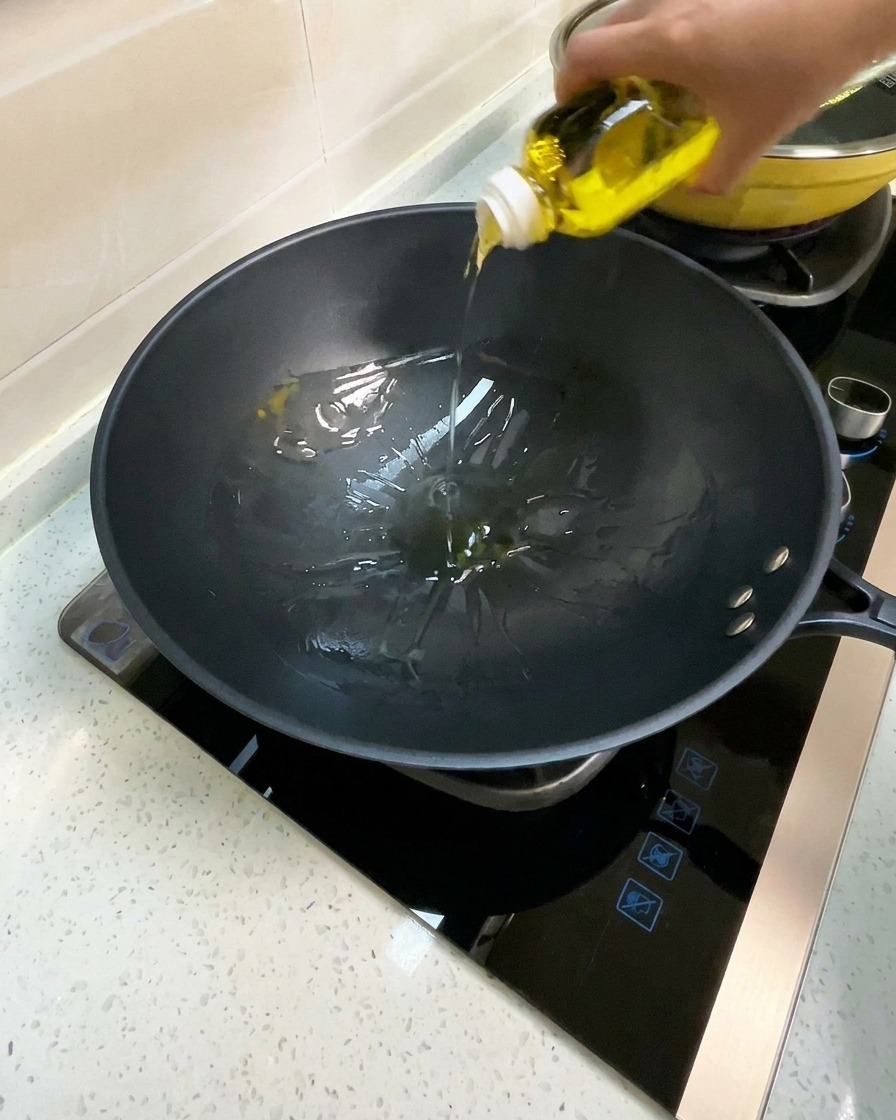 Huile de cuisson versée dans un wok noir préchauffé.