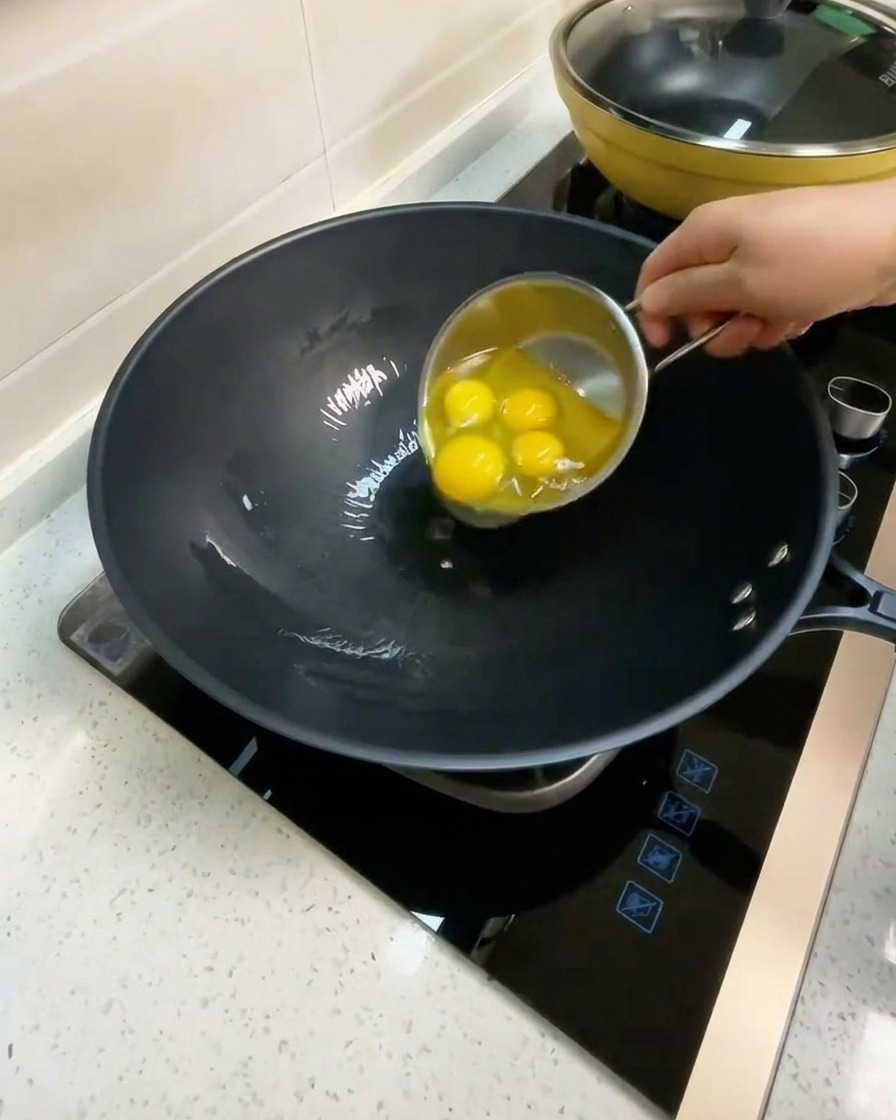 Quatre œufs crus cassés dans un wok avec de lhuile chaude.