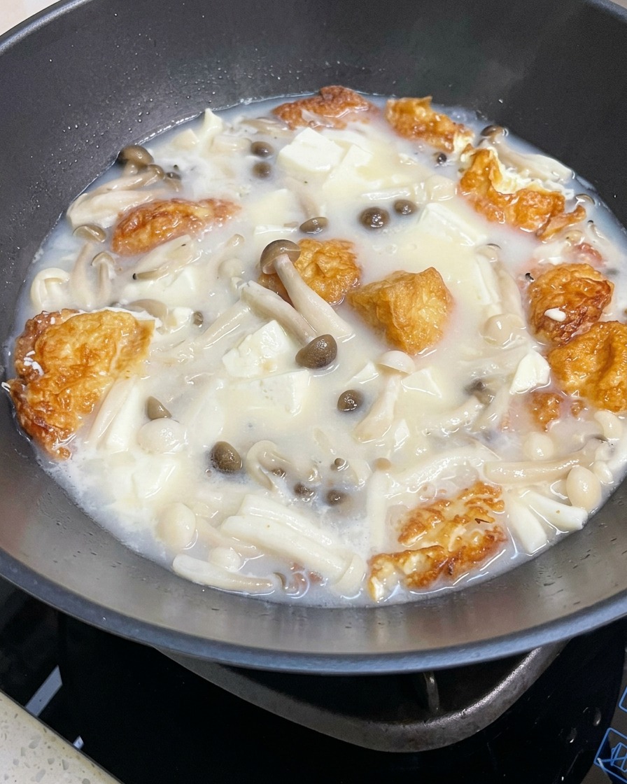 Gros plan sur la soupe de champignons et tofu mijotant, assaisonnée de sel et poivre.