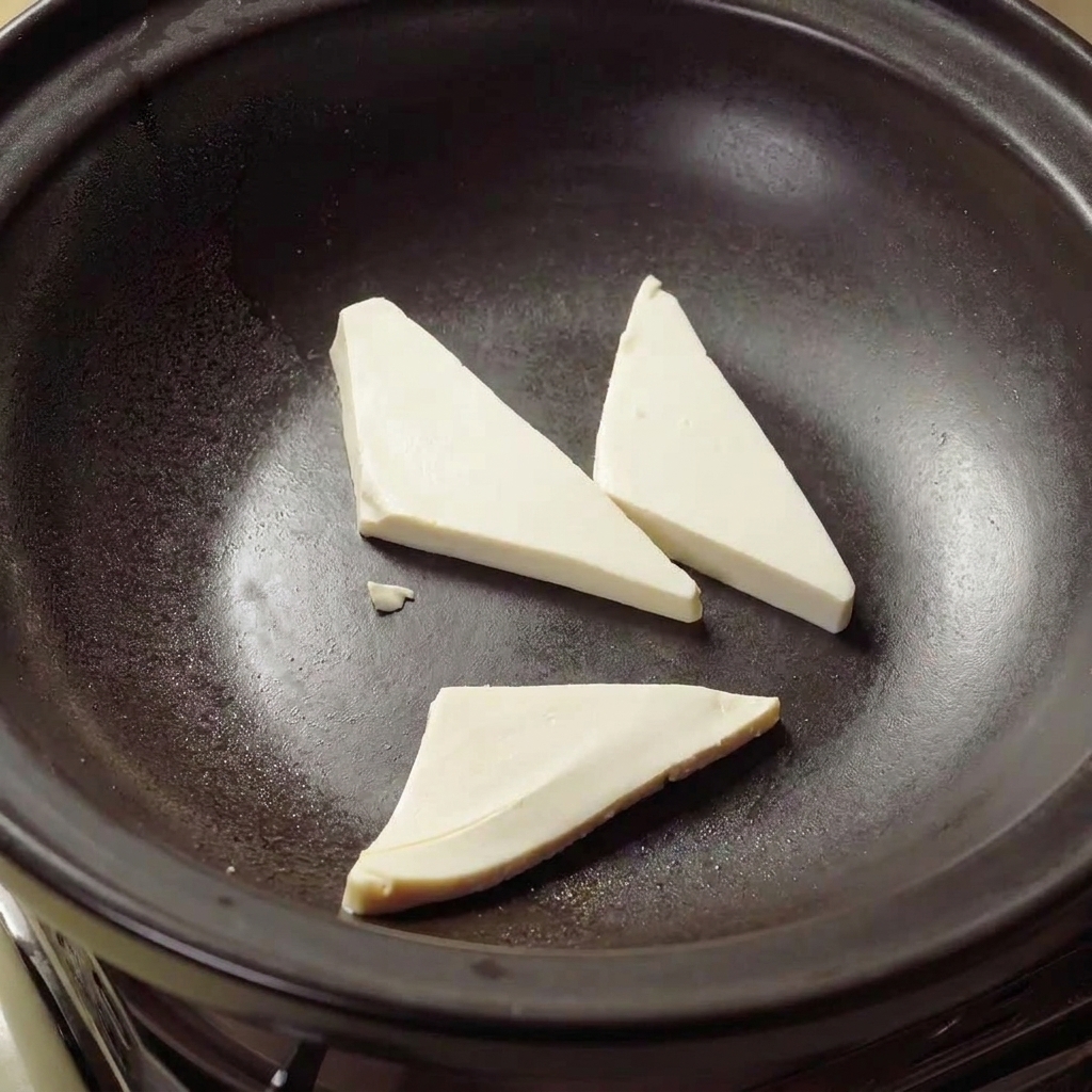 Triangles de tofu frits dans de lhuile chaude à lintérieur dun pot dargile jusquà ce quils soient dorés.