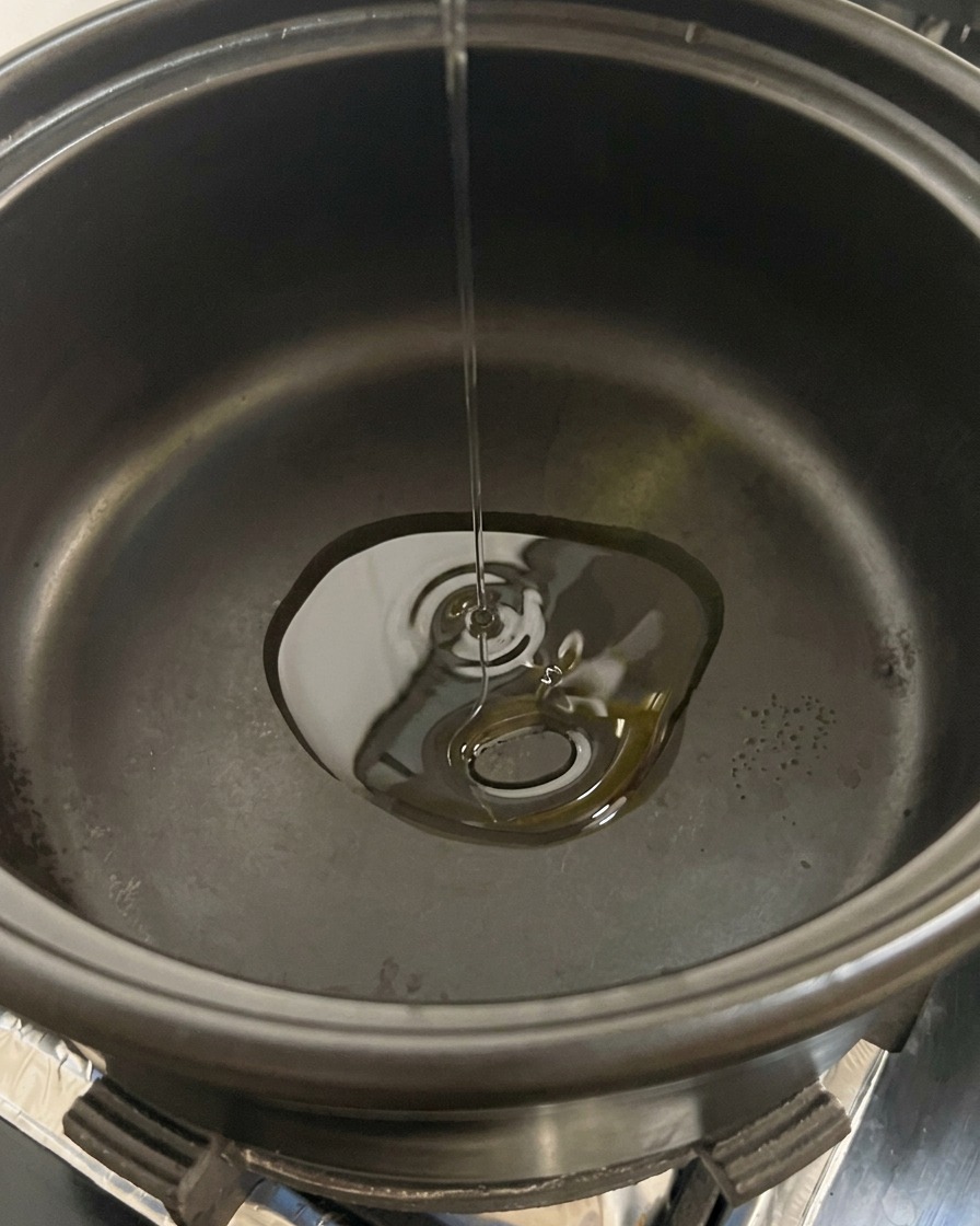 Champignons de Paris émincés versés dans une marmite noire contenant de lhuile chaude.