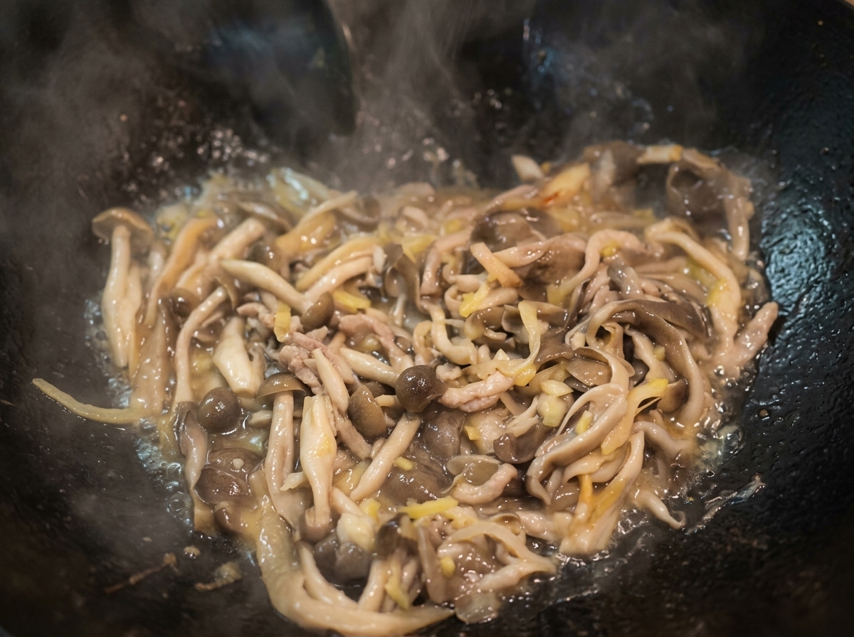 Eau bouillant dans un wok avec les champignons sautés, formant un bouillon léger.