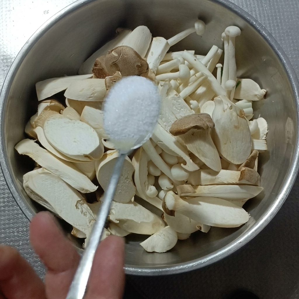 Pleurotes et champignons hêtre dans un bol en métal, en cours de nettoyage au sel.