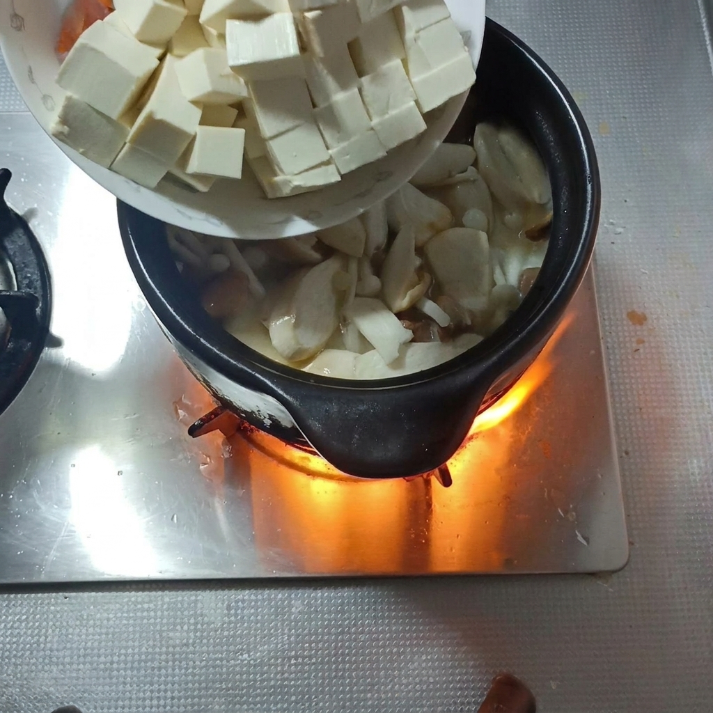 Cubes de tofu ferme et tranches de carottes ajoutés à la soupe aux champignons.