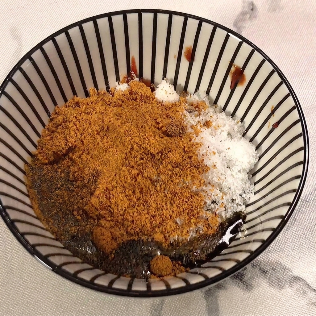 Sauce soja claire versée dans le mélange contenant la pâte de piment, le sucre et la poudre dassaisonnement.