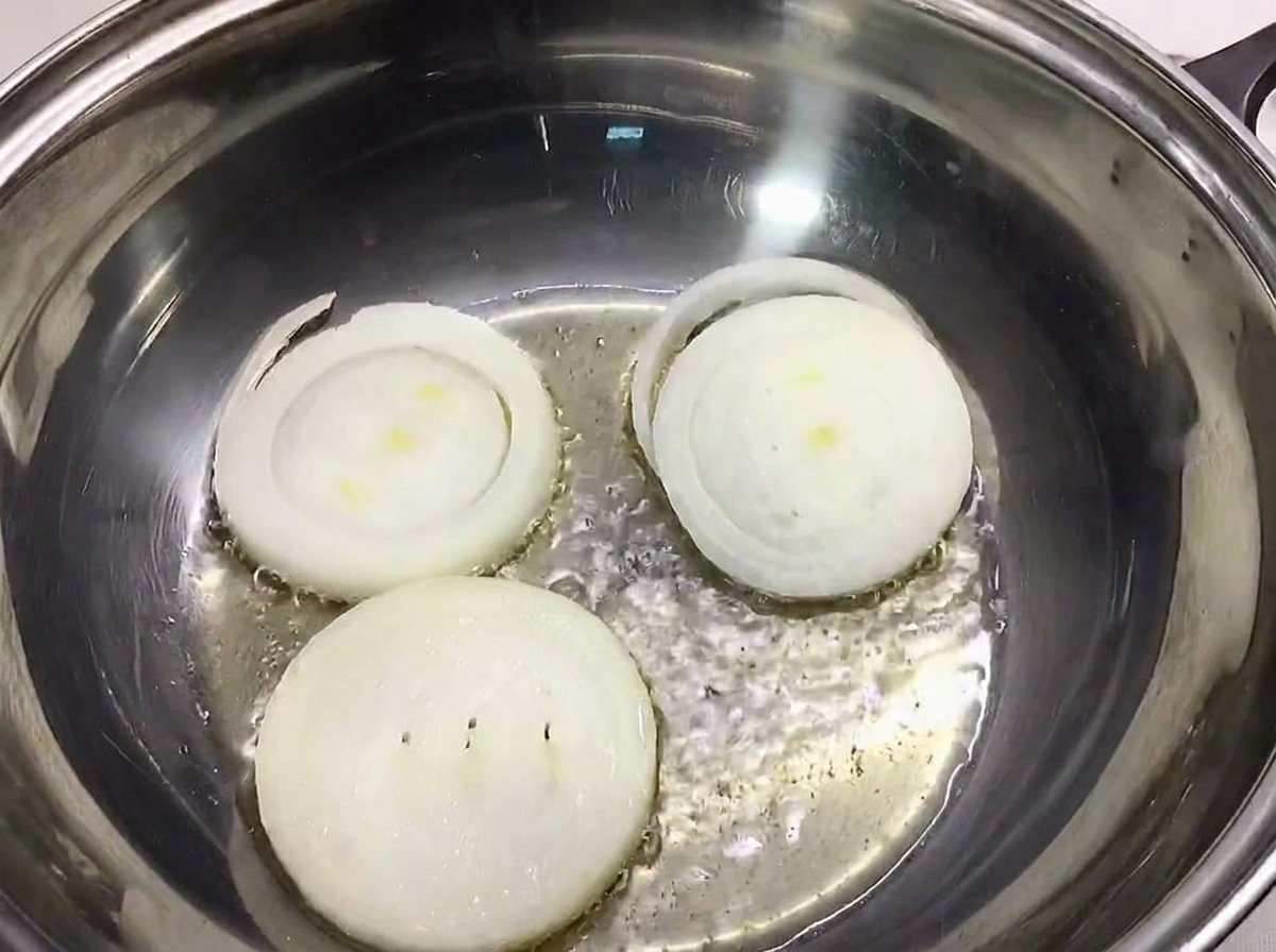 Trois tranches épaisses doignon blanc posées au fond dune marmite en inox.