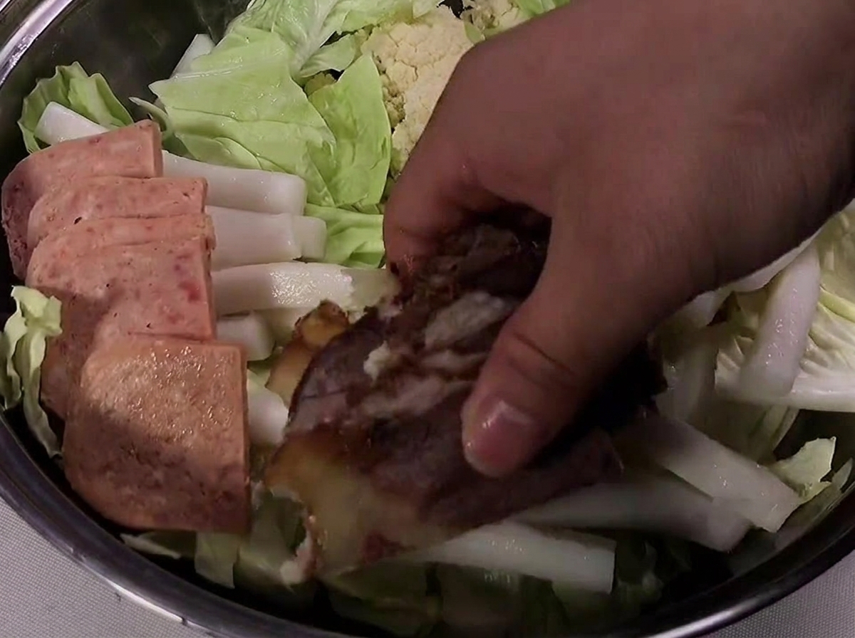 Tranches de Spam, bœuf cuit et saucisse soigneusement disposées sur le bord de la marmite.