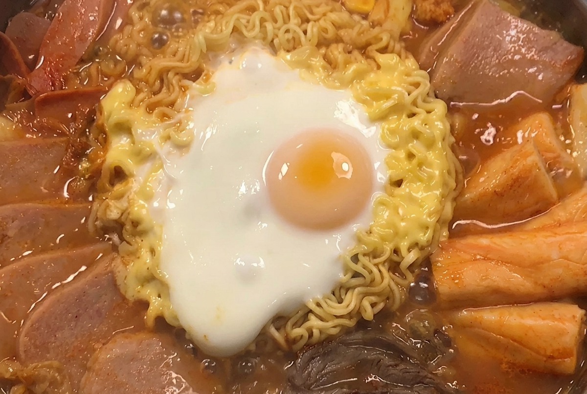 Marmite de ragoût garnie de grains de maïs jaunes et doignons verts émincés.