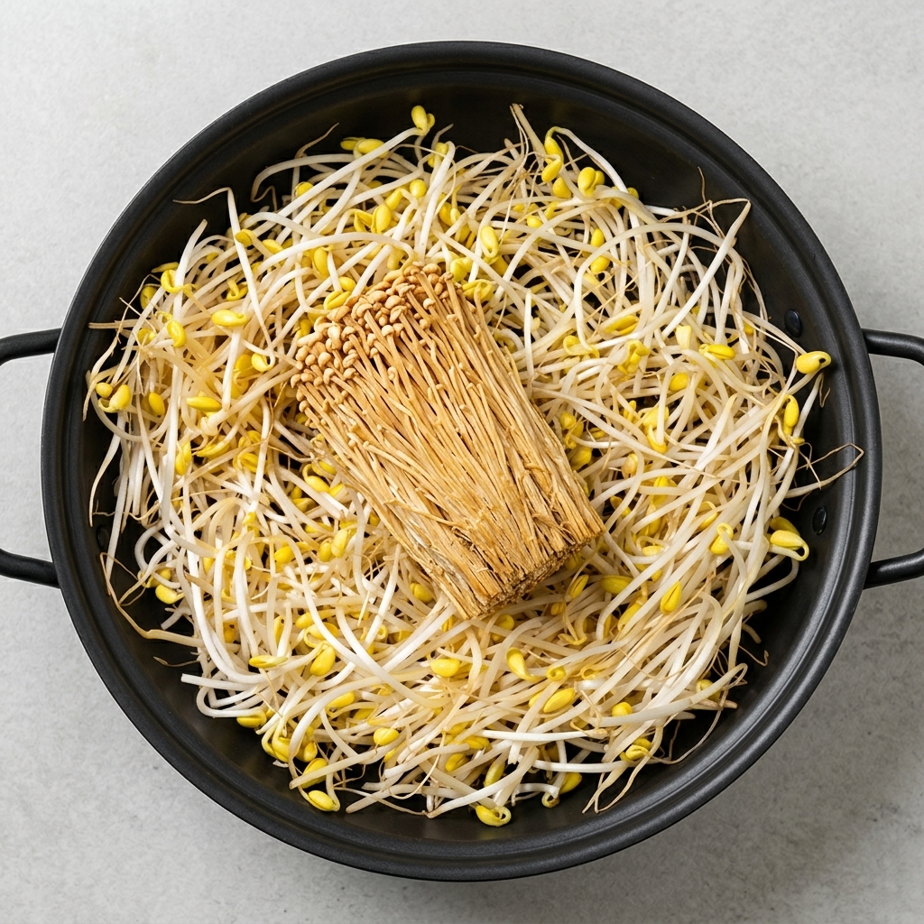 Une grande variété dingrédients préparés dont des pousses de soja, du tofu, des champignons enoki, du spam et des saucisses disposés soigneusement dans une marmite.