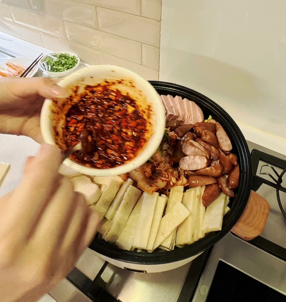 Un bol de sauce rouge vif versé sur larrangement coloré dingrédients dans une grande marmite à ragoût.