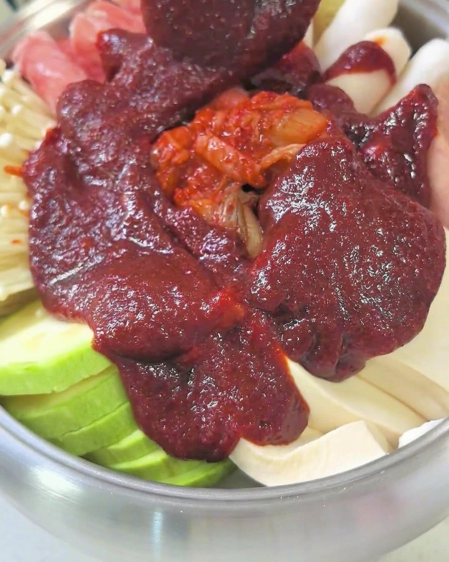 Une marmite remplie dingrédients et de bouillon, couverte dun couvercle, mijotant sur la cuisinière.