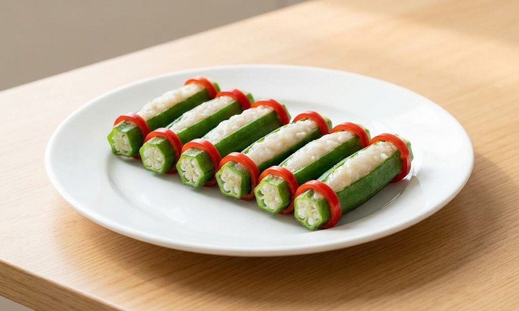 Une assiette blanche présentant des gombos farcis décorés de deux rondelles de piment rouge vif à chaque extrémité.