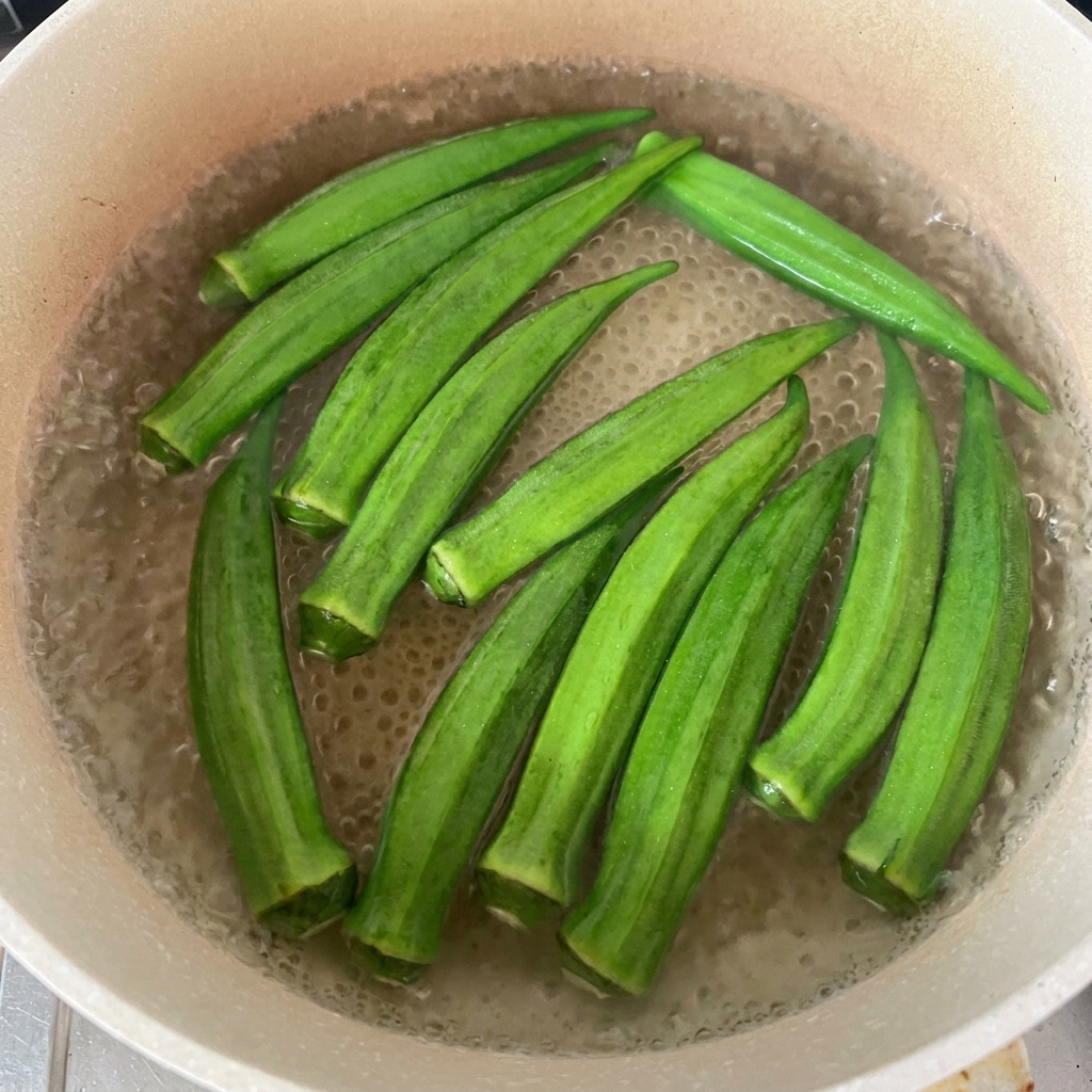 Gousses dokra vertes flottant dans une casserole deau frémissante.