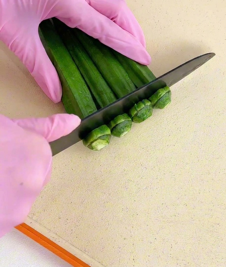 Mains gantées utilisant un couteau noir pour couper les tiges dun bouquet dokras verts.