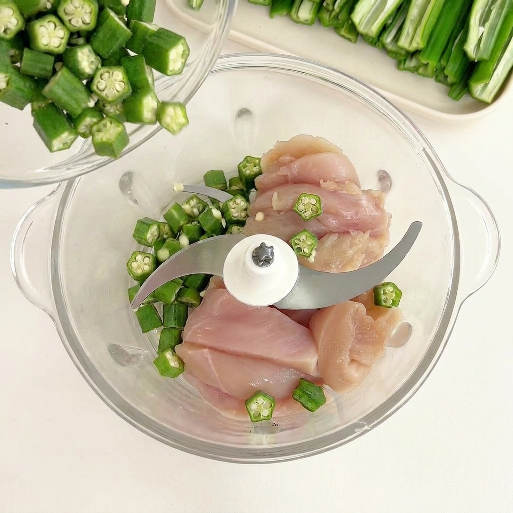 Graines dokra versées dun petit bol sur des morceaux de poulet cru dans un mixeur.