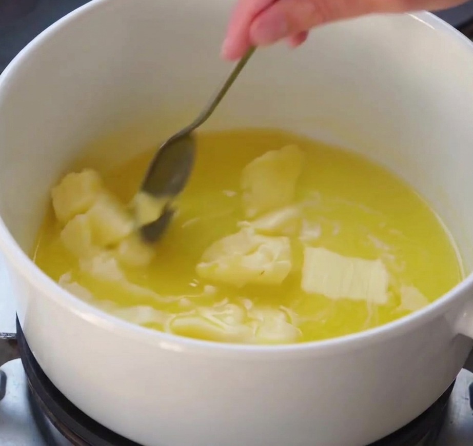 Un fouet mélangeant une sauce blanche lisse qui sépaissit dans une casserole sur la cuisinière
