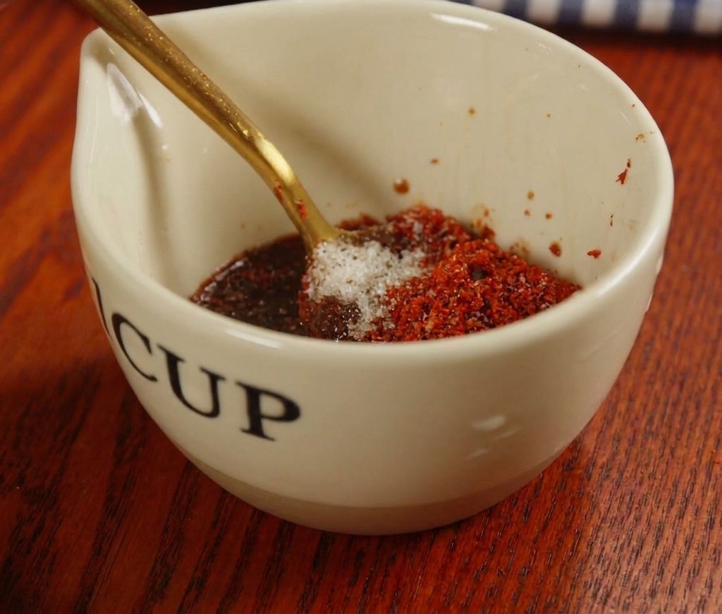 Mélange dune sauce rouge avec de la pâte de piment et des épices dans une petite tasse en céramique.