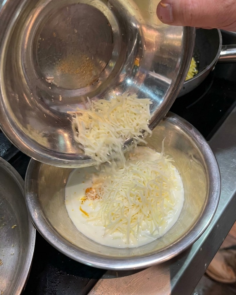 Parmesan râpé ajouté au bol contenant le mélange de jaune dœuf et de crème.