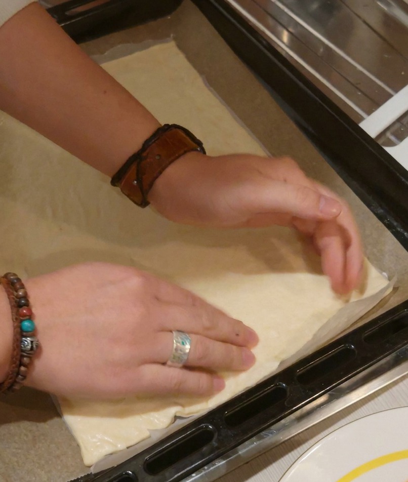 Deux mains pressant une pâte à pizza rectangulaire pour laplatir et définir les bords de la croûte.