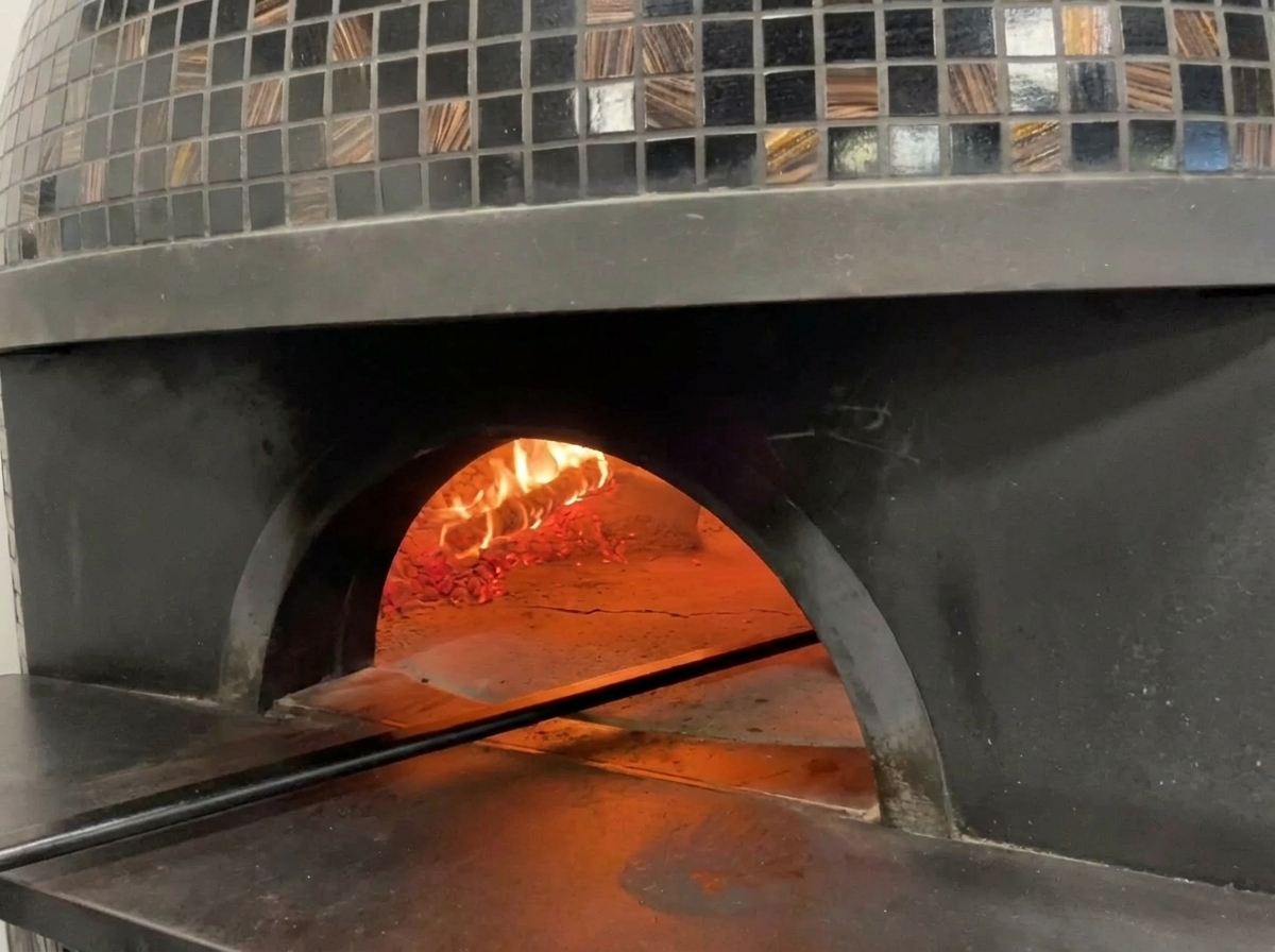 Vue de lintérieur dun four à pizza traditionnel avec des flammes et une pizza en train de cuire