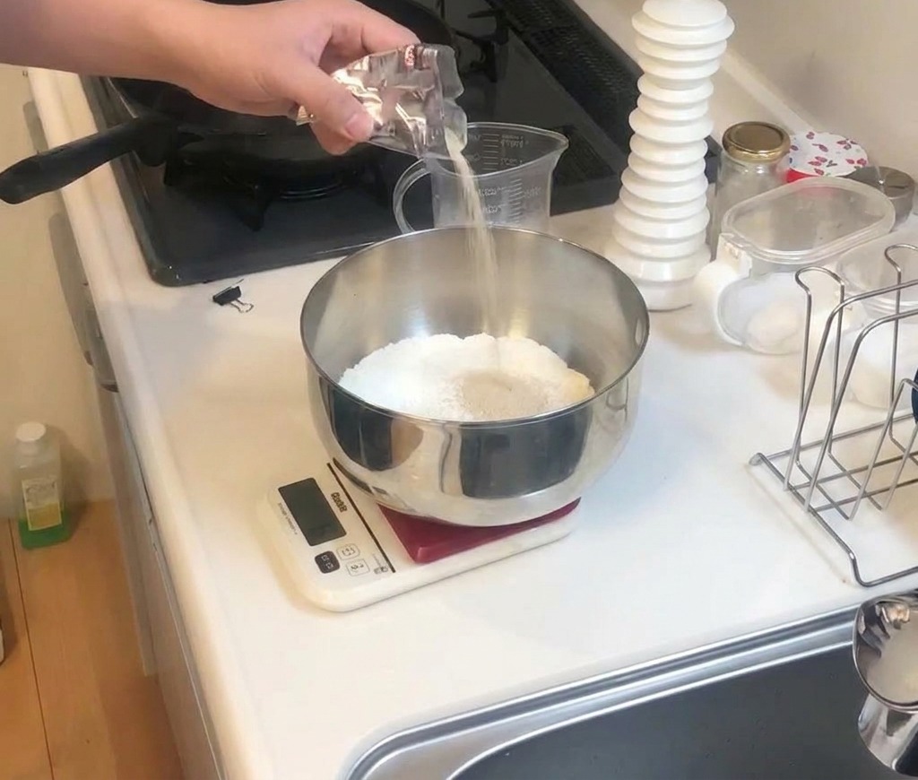 Une personne versant du sel depuis un petit sachet dans un bol en métal rempli de farine.