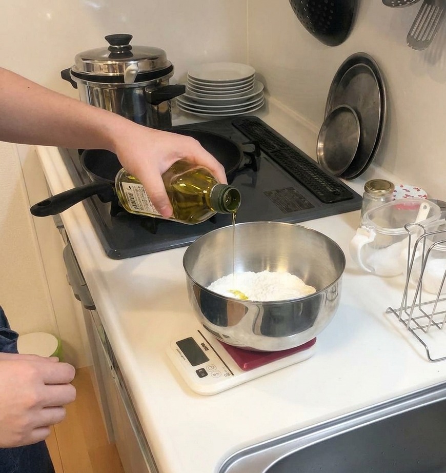 Un filet dhuile dolive versé depuis une bouteille en verre dans un bol contenant de la farine.