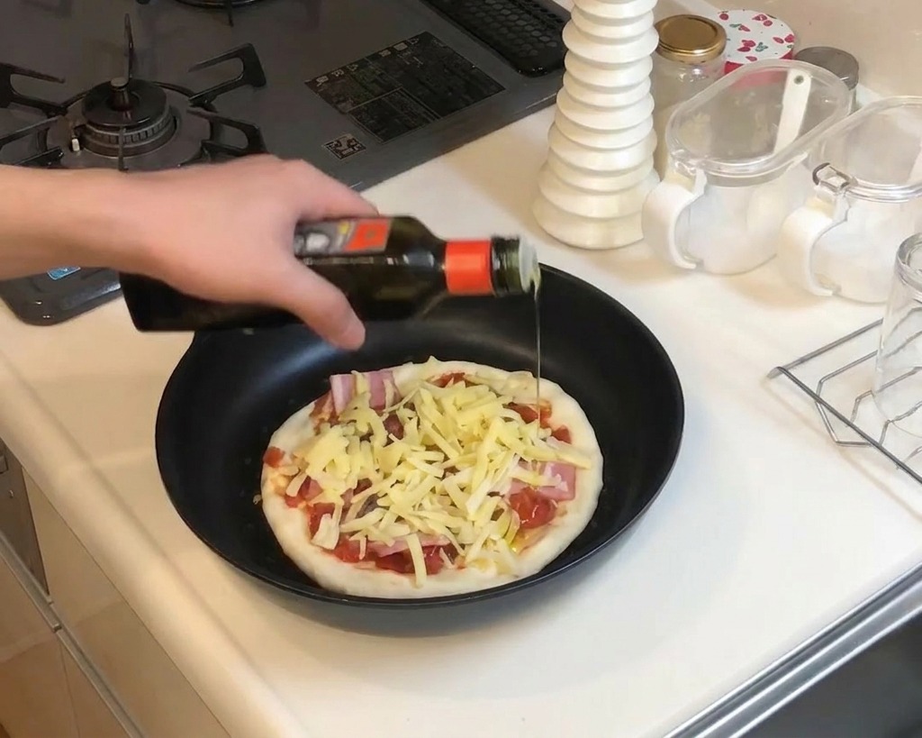 Gros plan sur un filet dhuile dolive versé sur une pizza garnie de fromage et de lardons dans une poêle.
